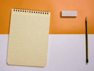 An empty notebook with an eraser on a yellow and white background. Close-up. Business concept.