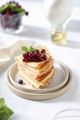 Thin pancakes in milk with berries on a white background