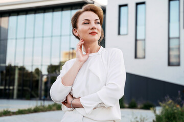 Portrait of pensive successful businesswoman wearing stylish clothing looking away standing on the street 