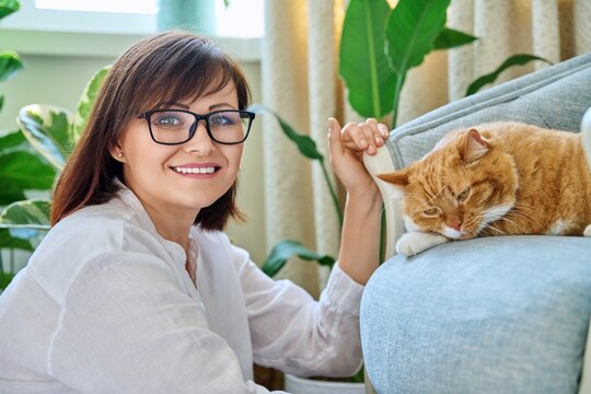 Portrait of smiling woman with pet cat lying on armchair in home