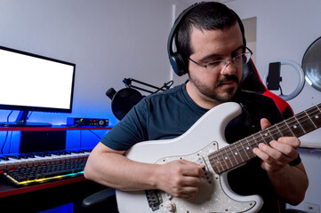 Fototapeta na wymiar young latin man in his home music studio recording with his electric guitar