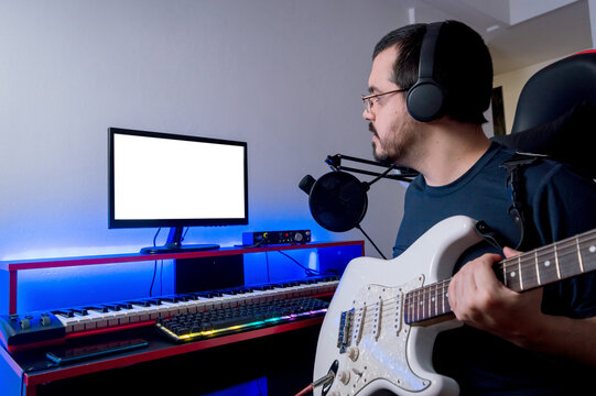 young latin man in his home music studio checking the recording he made with his electric guitar