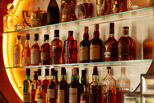 Whiskey and a lot of premium alcoholic drinks bottles in a bar like Highland Park, Glenlivet, Glefarclas or Aberlour. Fine drinks industry.