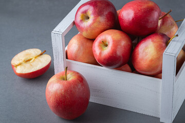 Fresh red apples in a wooden box on a grey background. Organic food