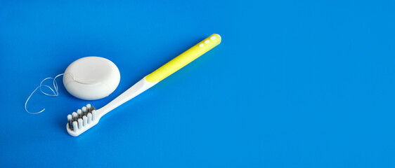 Dental floss and toothbrush on a blue background. Dental care.
