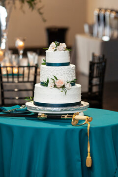 Three tiered wedding cake with sword for military wedding reception.
