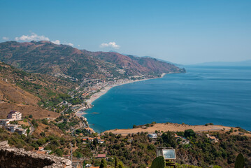 High angle view of scenic landscape at Mediterranean seacoast. Scenic seascape and coastal town with blue sky in background. Idyllic scenery of nature and urban land.