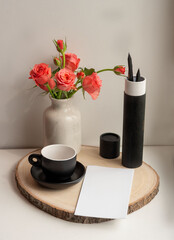 minimalistic composition with stationery and a vase of roses on a wooden stand