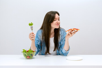 Young beautiful woman on a diet wants to choose pizza instead of salad