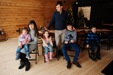 Fototapeta na wymiar Family in modern wooden house sitting against table with christmas tree, spending time together in warm and love.