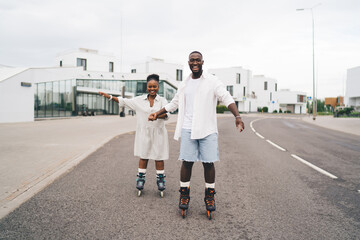 Cheerful ethnic couple roller skating on road on urban street