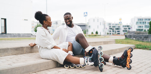 Smiling African American man and woman sitting on pavement