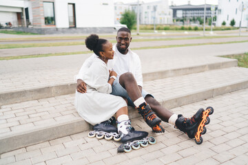 African American couple in inline skates sitting on pavement stairs