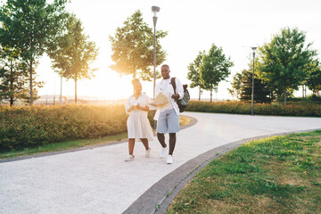 Fototapeta premium Happy ethnic couple walking in park with map