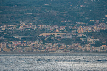 Obraz premium Beautiful view of old Messina harbor cityscape and the Mediterranean sea. Residential houses in ancient town of island. View of townscape at seacoast with waterfront.