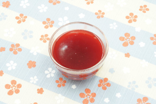 Raspberry kissel on a tablecloth with flowers. Jelly in a round glass dish. Delicious sweet fruit boiled in water with potato flour.
