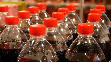 Close-up of many plastic bottles of cola with red caps
