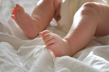 Baby Legs Close up on White Blanket. Healthy Newborn Feet. Warm Sunlight. Beautiful Shot of Infant's Small Feet on a Light Background. Early age children development. Authentic Candid Lifestyle.