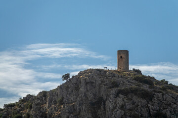 Fototapeta na wymiar Atalaya de Deifontes (Spain) on a rocky hill surrounded by oaks on a sunny summer morning