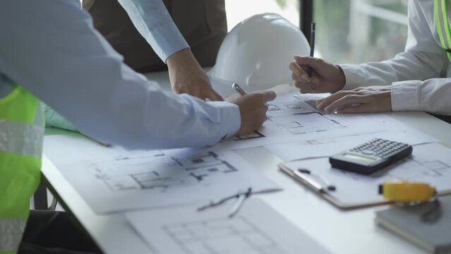 construction meeting construction with builders Architects and Engineers and inspector They were looking at the various planning blueprints in the office. 4K stock video clip.