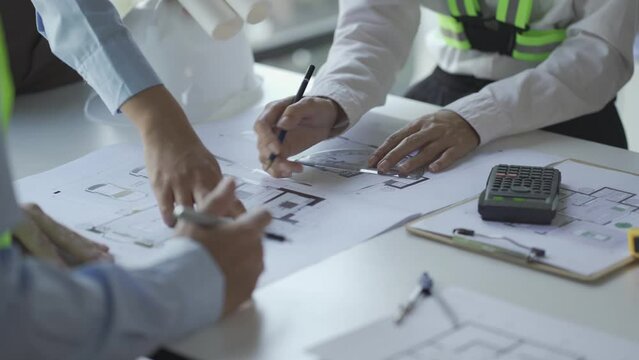 construction meeting construction with builders Architects and Engineers and inspector They were looking at the various planning blueprints in the office. 4K stock video clip.