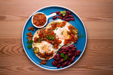 Ranch eggs with beans. Traditional Mexican recipe with fried eggs in a paella and corn pancakes