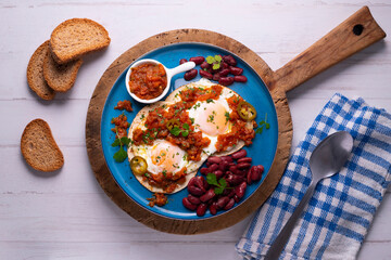 Ranch eggs with beans. Traditional Mexican recipe with fried eggs in a paella and corn pancakes