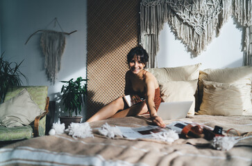 Young woman with laptop and magazine on bed