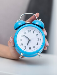 Close up photo of female hand holding alarm clock. Wake up and hurry up concept