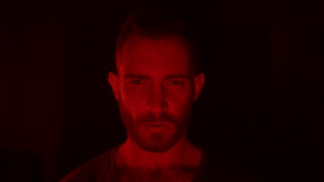 Angry man looking at camera with fury and rage, his face lit with fire flames of his personal hell, grief and sorrow. Male starring at viewer with aggresive emotions and insane devilish look.
