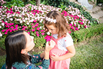 daughter and mother playing with a flower in the park