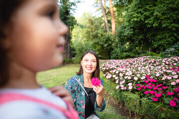 daughter and mother playing with a flower in the park
