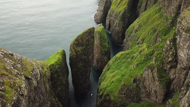 Aerial drone view of Dunnesdrangar, Faroe Islands. Amazing nature, huge cliffs and mountains in Faroe Islands. Vagar Island. Many flying sea birds. Sunny day in summer. High quality 4k footage. 