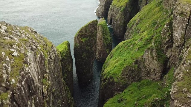Aerial drone view of Dunnesdrangar, Faroe Islands. Amazing nature, huge cliffs and mountains in Faroe Islands. Vagar Island. Many flying sea birds. Sunny day in summer. High quality 4k footage. 