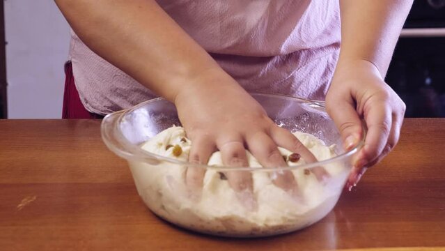 Women's hands knead the dough rolled out on the table. Medium plan