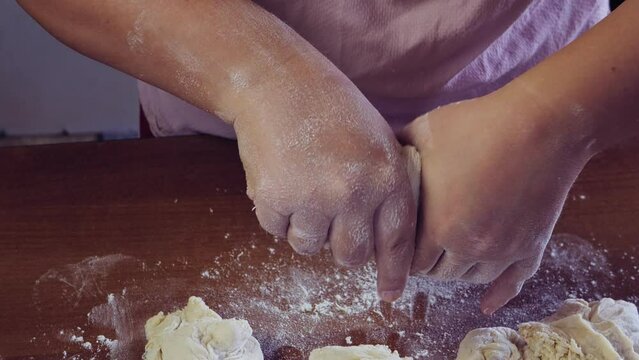 Women's hands scatter white flour on a wooden table. Medium plan