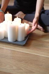 Women's hands light candles with matches. Yoga practice and fire in the palms