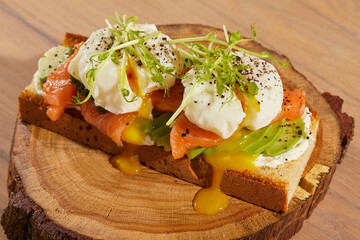 the cook prepares a sandwich with fish and an egg on a dark background