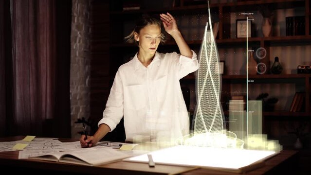 Attractive middle aged architect  working on a futuristic hologram building for urban architecture project and make notes on architectural drawings.