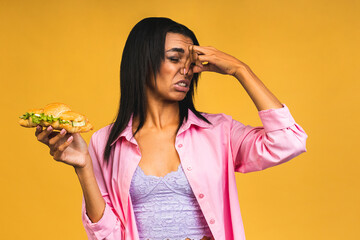 African american woman standing over isolated over yellow background smelling something stinky and...
