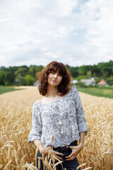 A girl in a field of yellow wheat on the background of a rainy sky