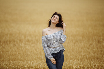 A girl in a field of yellow wheat on the background of a rainy sky