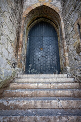 Fototapeta na wymiar Looking up towards closed solid door of medieval walled castle.