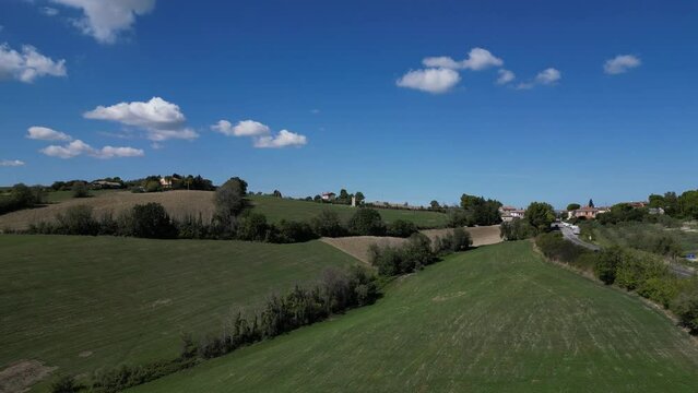 Verdi colline con cielo nuvoloso, con una piccola strada che li costeggia