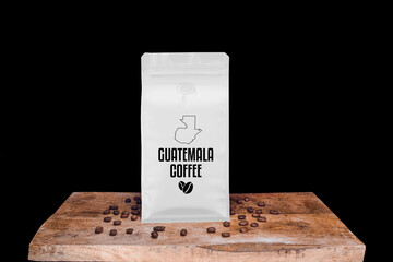 Guetamala coffee beans and white package on wooden board with black isolated background