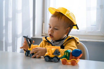 Obraz na płótnie Canvas Child play with construction machinery at home, dreams to be an engineer. Little builder. Education, and imagination, purposefulness concept. Boy with digger