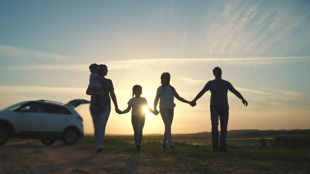 people in the park. happy family a silhouette walk at sunset. car travel kid dream concept. happy family parents and children walk silhouette next to car. family walk next to car sun