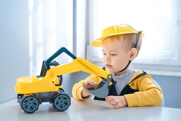 Fototapeta na wymiar Boy with digger. Child play with excavator at home, dreams to be an engineer. Little builder. Education, and imagination, purposefulness concept
