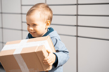 Child parcel, boy using self service parcel terminal machine to send or receive package. Parcel...