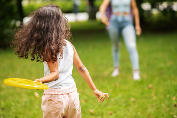 active entertainment outside, african girl with frisbee disc playing with mom in the park, family...
